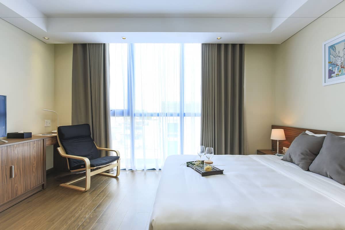A hotel room with a bed, a desk, a chair, a television, and a window with curtains.
