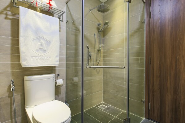 Een moderne badkamer met een douche met glazen wand, een toilet en een handdoek aan de muur.