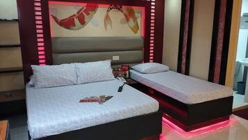 Een moderne hotelkamer met een groot bed, een klein bed en een rode stoel.