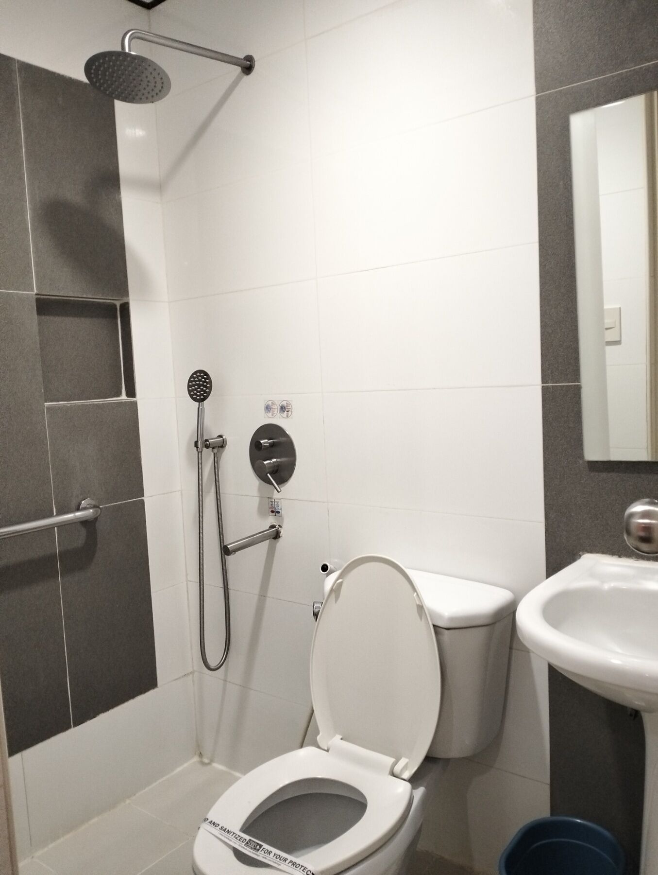 A modern bathroom with a shower, toilet, and sink.