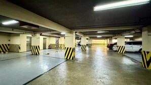An underground parking garage with multiple levels, concrete floors, and yellow and black striped barriers. - Hotel Sogo Roxas Blvd (Pasay)