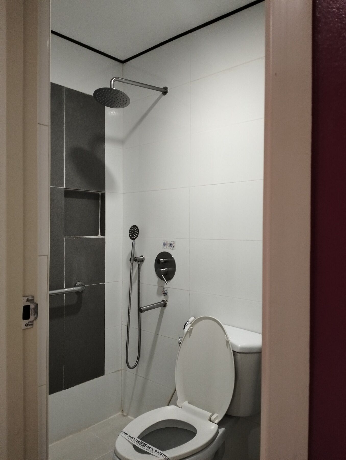A small bathroom with a shower, toilet, and a towel rack.