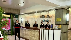 A hotel reception desk with staff members, a clock, and a sign indicating minors are not allowed. - Hotel Sogo Roxas Blvd (Pasay)