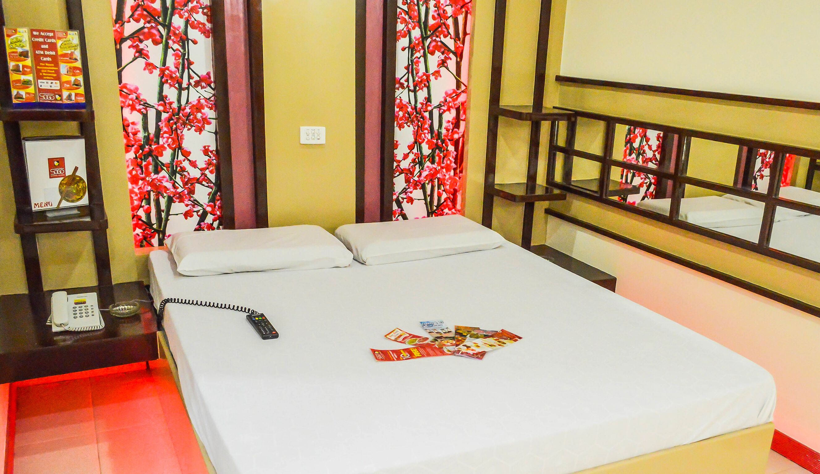 A hotel room with a bed, a telephone, and a menu board.