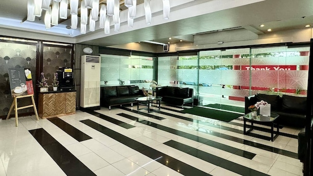 A modern reception area with a check-in counter, seating area, and a large window with a 'Thank You' sign. - Hotel Sogo Roxas Blvd (Pasay)