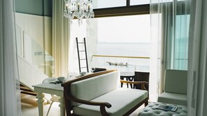 A modern room with a view of the sea, a dining area, and a staircase. - The Beach Samui (Koh Samui)
