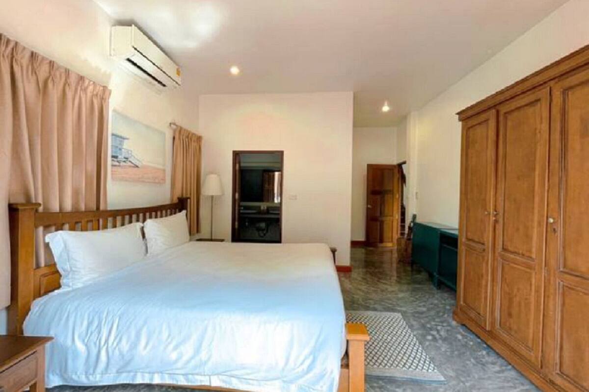 A hotel room with a bed, a wardrobe, a mirror, and an air conditioning unit.