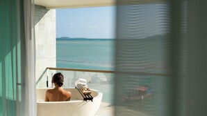 A bathroom with a bathtub, a towel rack, and a view of the sea. - The Beach Samui (Koh Samui)