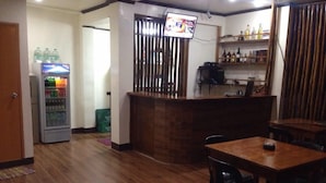 A restaurant with a wooden floor, a counter with a TV, and a vending machine. - Lolo Bob's Bed And Breakfast (El Nido)
