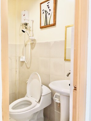A bathroom with a toilet, bidet, and a showerhead. - Lolo Bob's Bed And Breakfast (El Nido)