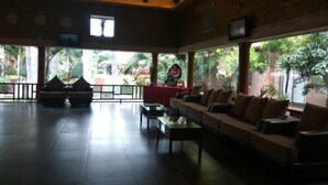 A spacious lobby with a long sofa, a small table, and a red tablecloth. - Golden Amoon Resort (Hoskote)