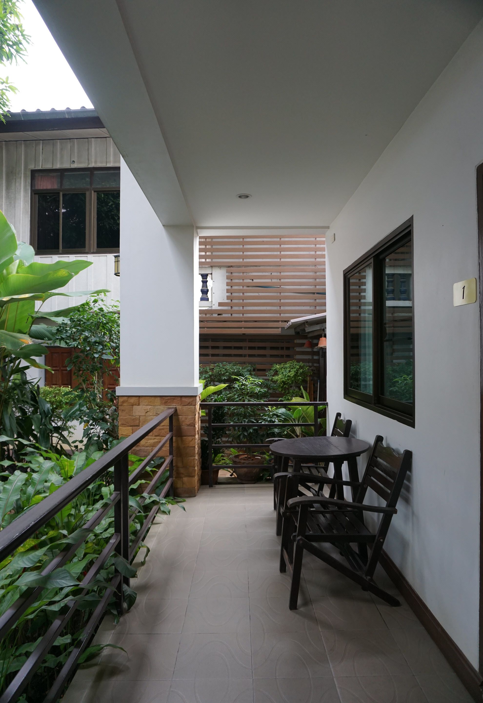 A balcony with a table and chairs, surrounded by plants and a railing.