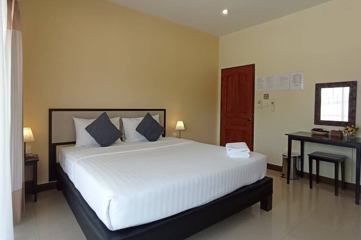 A hotel room with a large bed, bedside tables, a desk, and a chair.