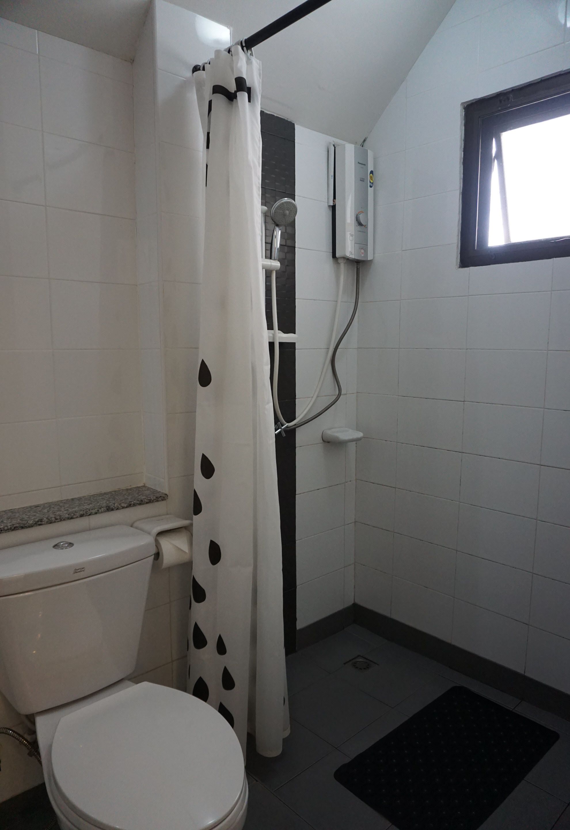 Un baño pequeño con inodoro, ducha y ventana.