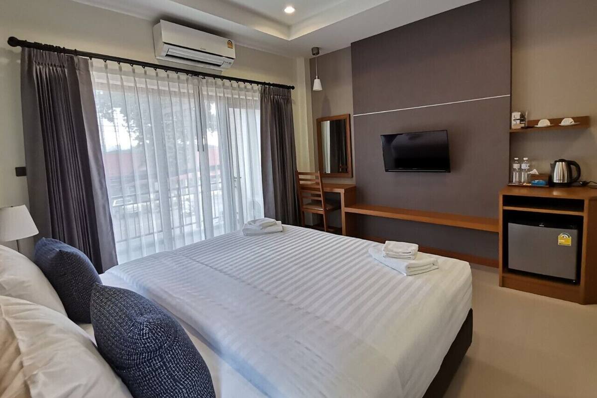 A hotel room with a large bed, a desk, a TV, and a minibar.