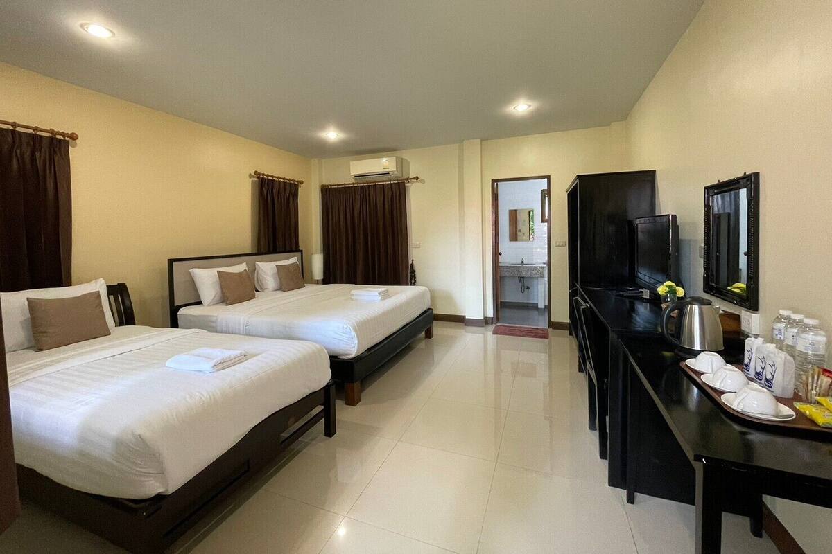 A hotel room with two beds, a desk with a TV, and a bathroom visible through an open door.
