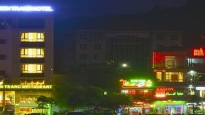 A hotel with illuminated signage, a restaurant, and various shops in the background. - White Lotus (Lao Cai)