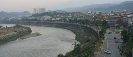 Un río con un puente, una carretera con coches y edificios al fondo.