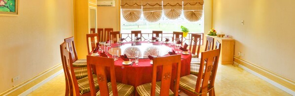 A dining area with a round table, wooden chairs, and a red tablecloth.