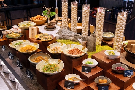 A buffet with various dishes and a bonsai tree.