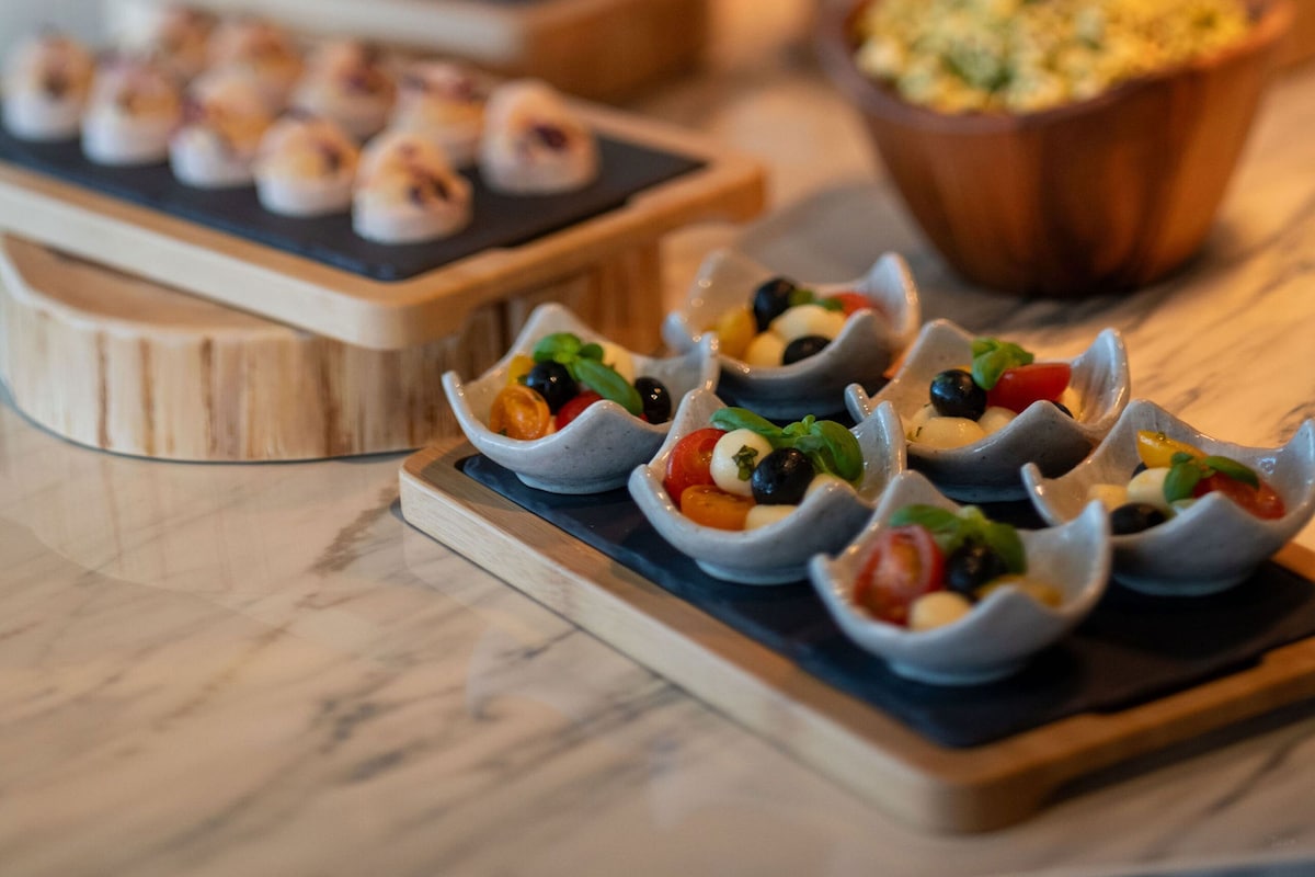 Un buffet con diversi piatti, tra cui insalate servite in piccole ciotole e altre specialità.