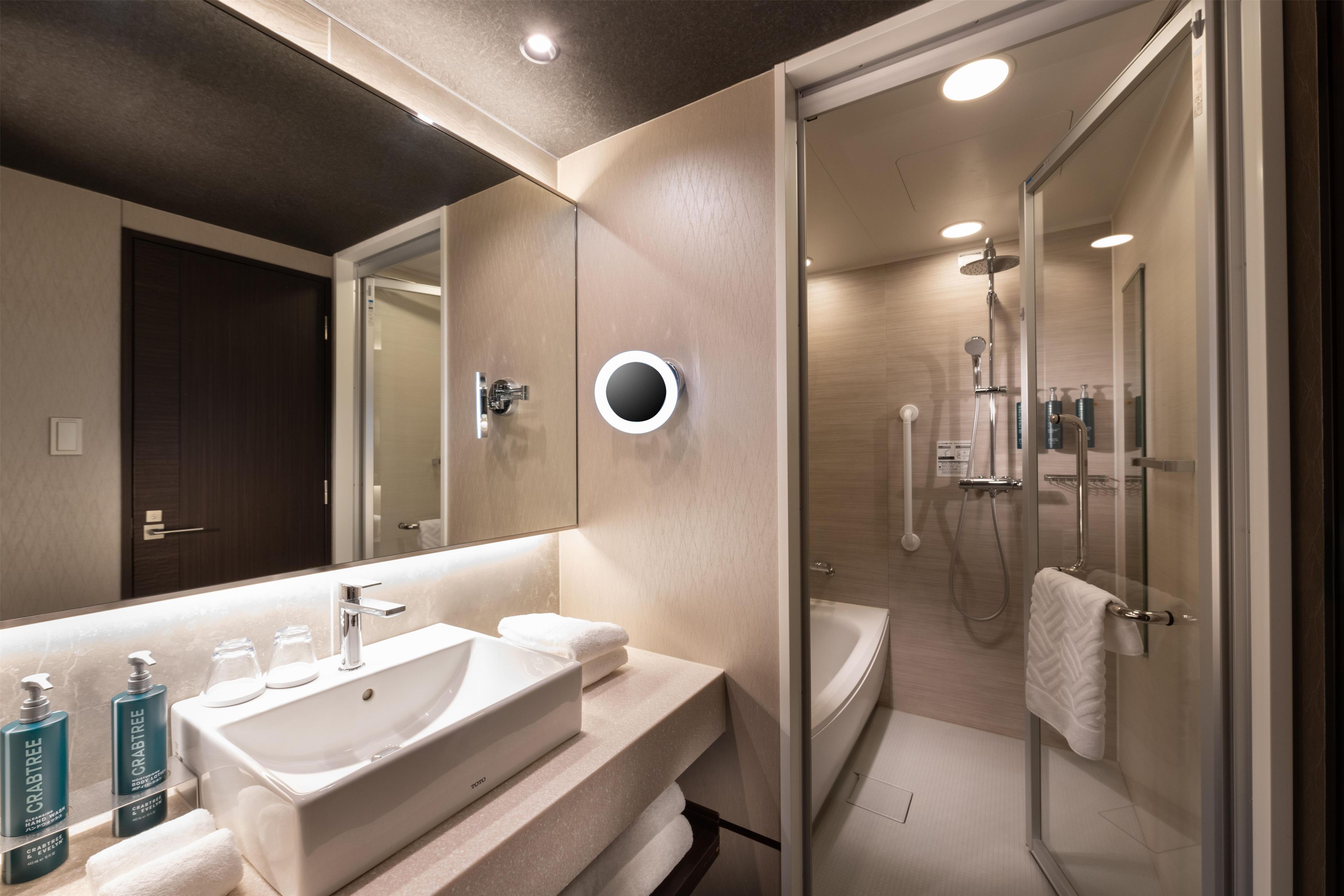 A modern bathroom with a large mirror, a sink, and a shower area.