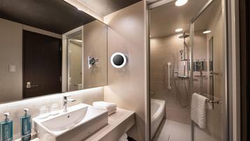 Un baño moderno con un espejo grande, un lavabo y una zona de ducha.
