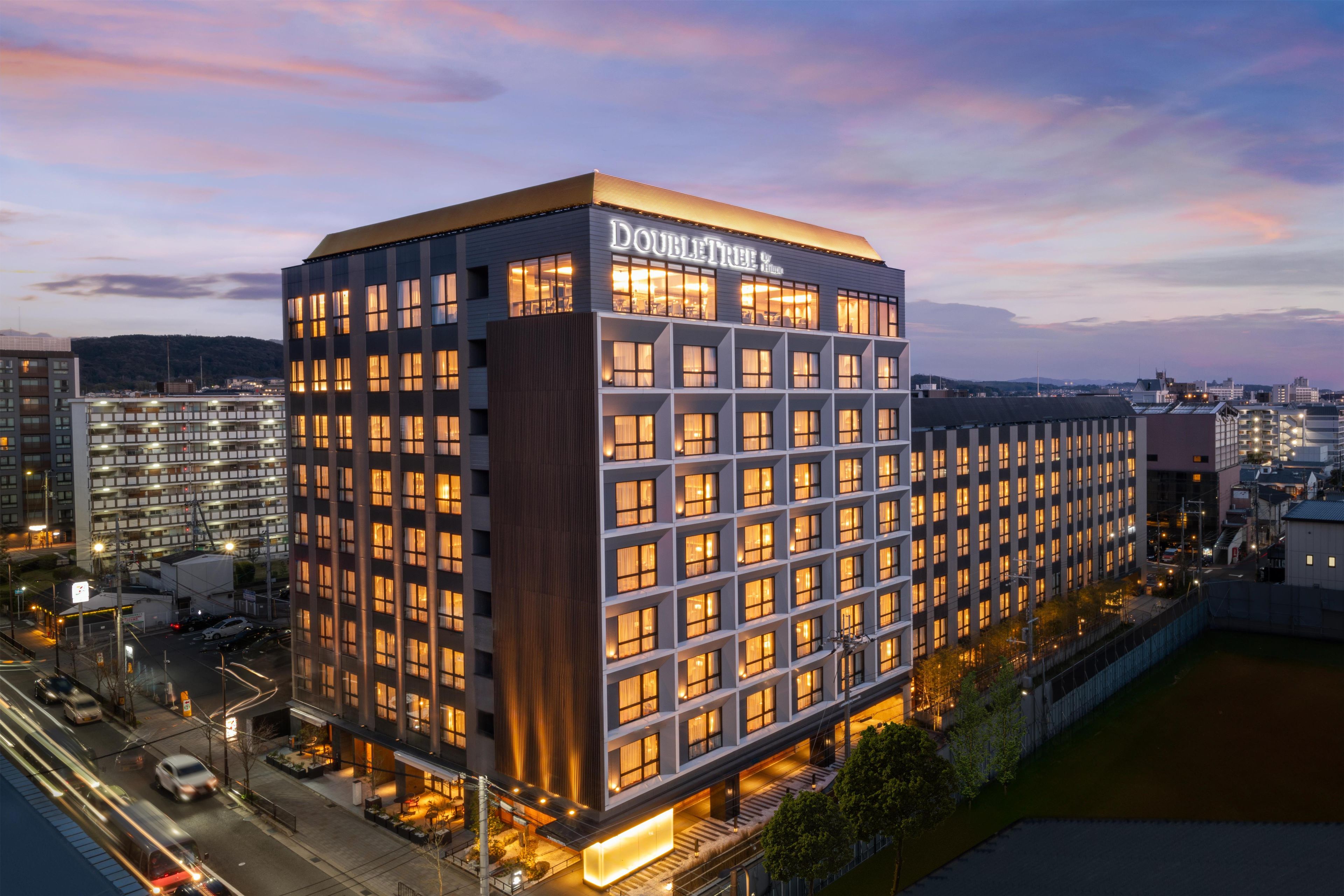 Um edifício moderno de hotel com uma placa chamativa 'DOUBLETREE', vários andares e fachada bem iluminada.