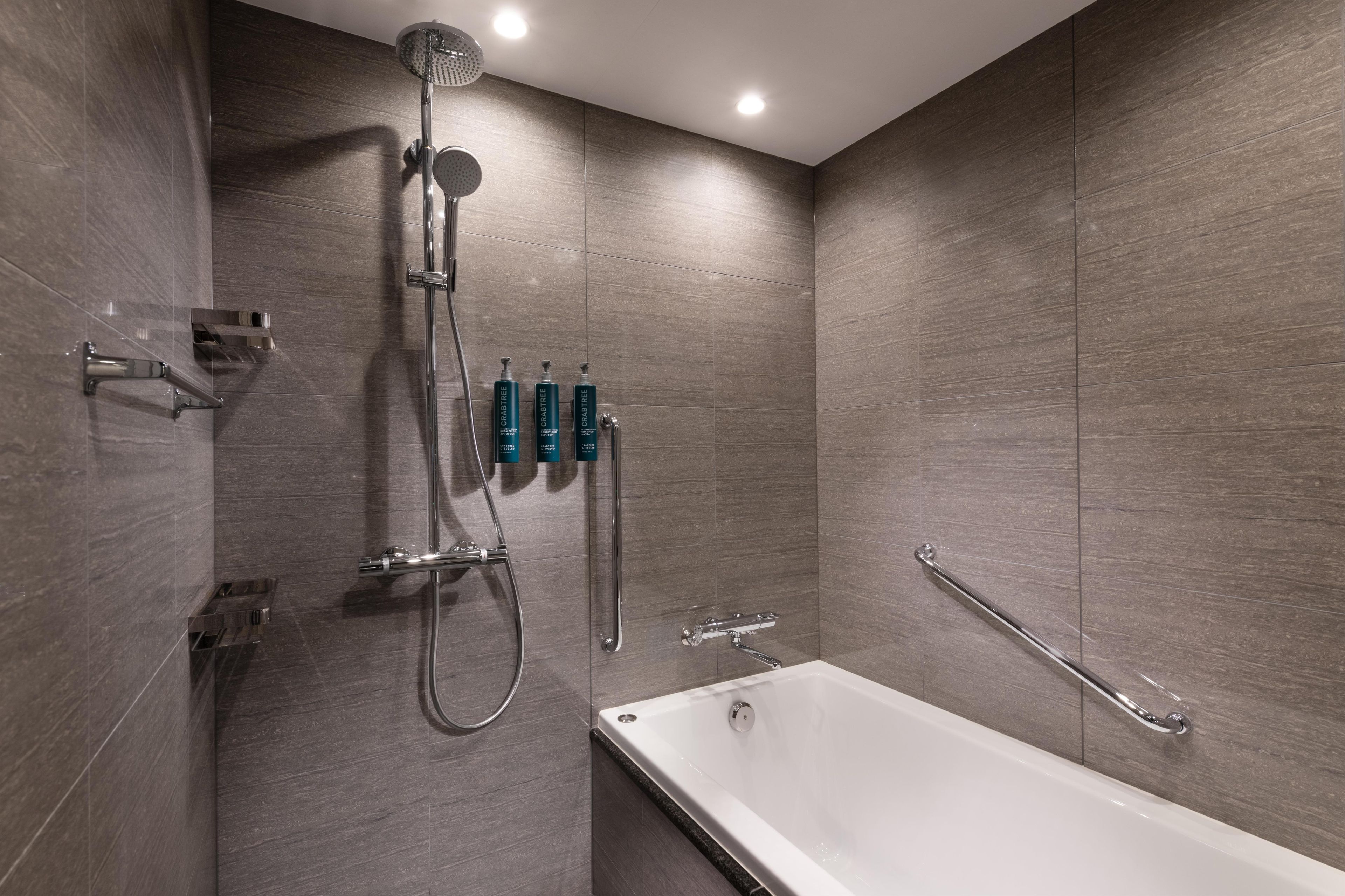 Een moderne badkamer met een badkuip, douche en handgrepen.