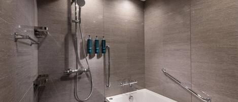 Een moderne badkamer met een badkuip, douche en handgrepen.