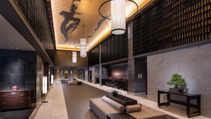 A modern lobby with a long corridor, seating areas, and a fireplace.