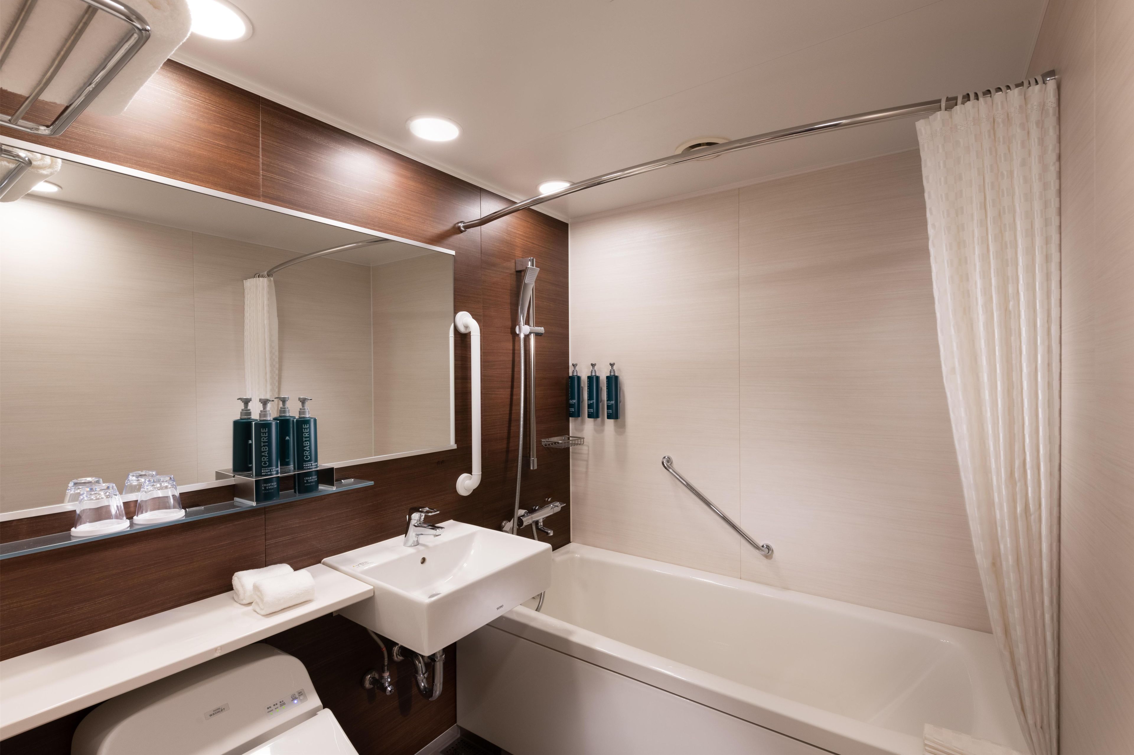 Een moderne badkamer met een bad, een wastafel, een spiegel en een douche.