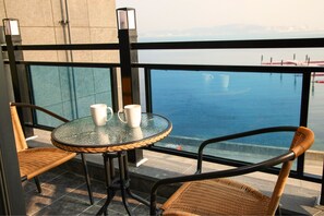 A balcony with wicker chairs, a glass table, and two white mugs. - Busan Pension Chaeum (Busan)