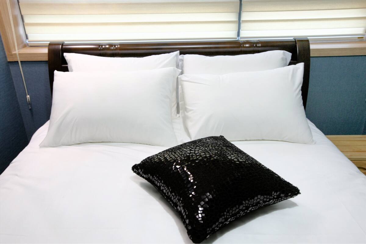 Ein Bett mit weißen Kissen und einem schwarzen Paillettenkissen.