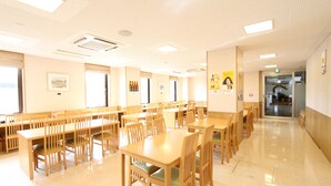 A spacious dining area with multiple wooden tables and chairs, large windows, and a clean, well-lit interior. - Hotel Inn Tsuruoka (Tsuruoka)