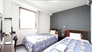 A hotel room with two beds, a desk, a television, and a window with curtains. - Hotel Inn Tsuruoka (Tsuruoka)