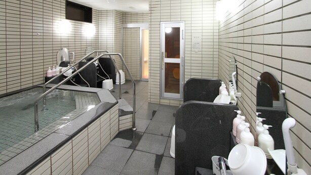 A bathroom with a bathtub, a shower area, and a sink with toiletries. - Hotel Inn Tsuruoka (Tsuruoka)