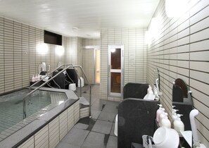 Un baño con bañera, cabina de ducha y lavamanos con artículos de aseo.