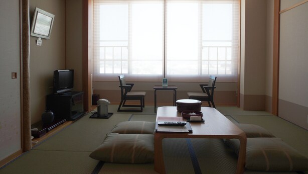 A traditional Japanese-style room with tatami flooring, a low table, cushions, a television, and a large window with sliding doors. - Attamari Land Fukabori (Oishida)