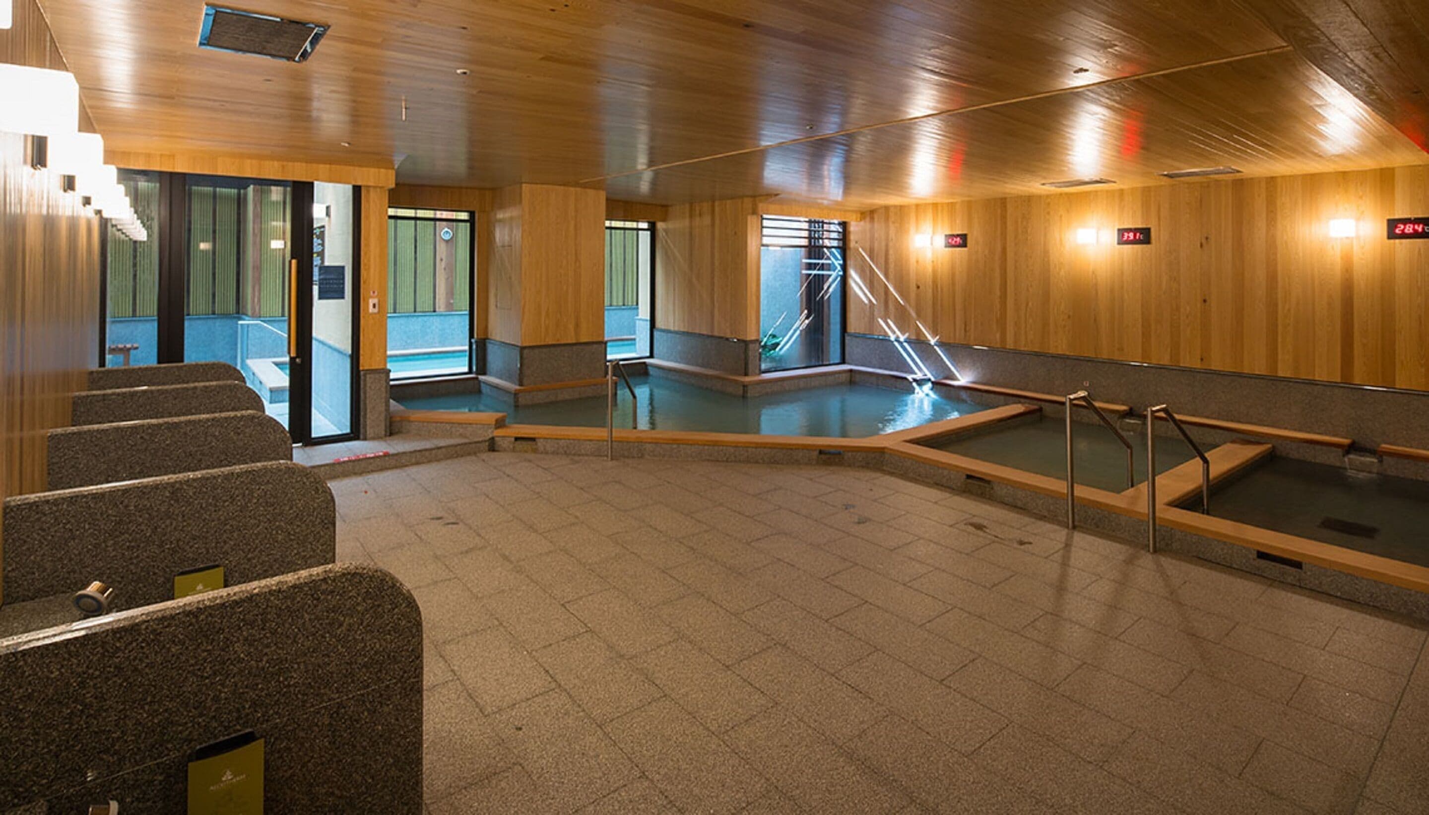 En moderne indendørs swimmingpool med trævægge og stengulv.