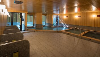 Una piscina interior moderna con paredes de madera y suelo de piedra.
