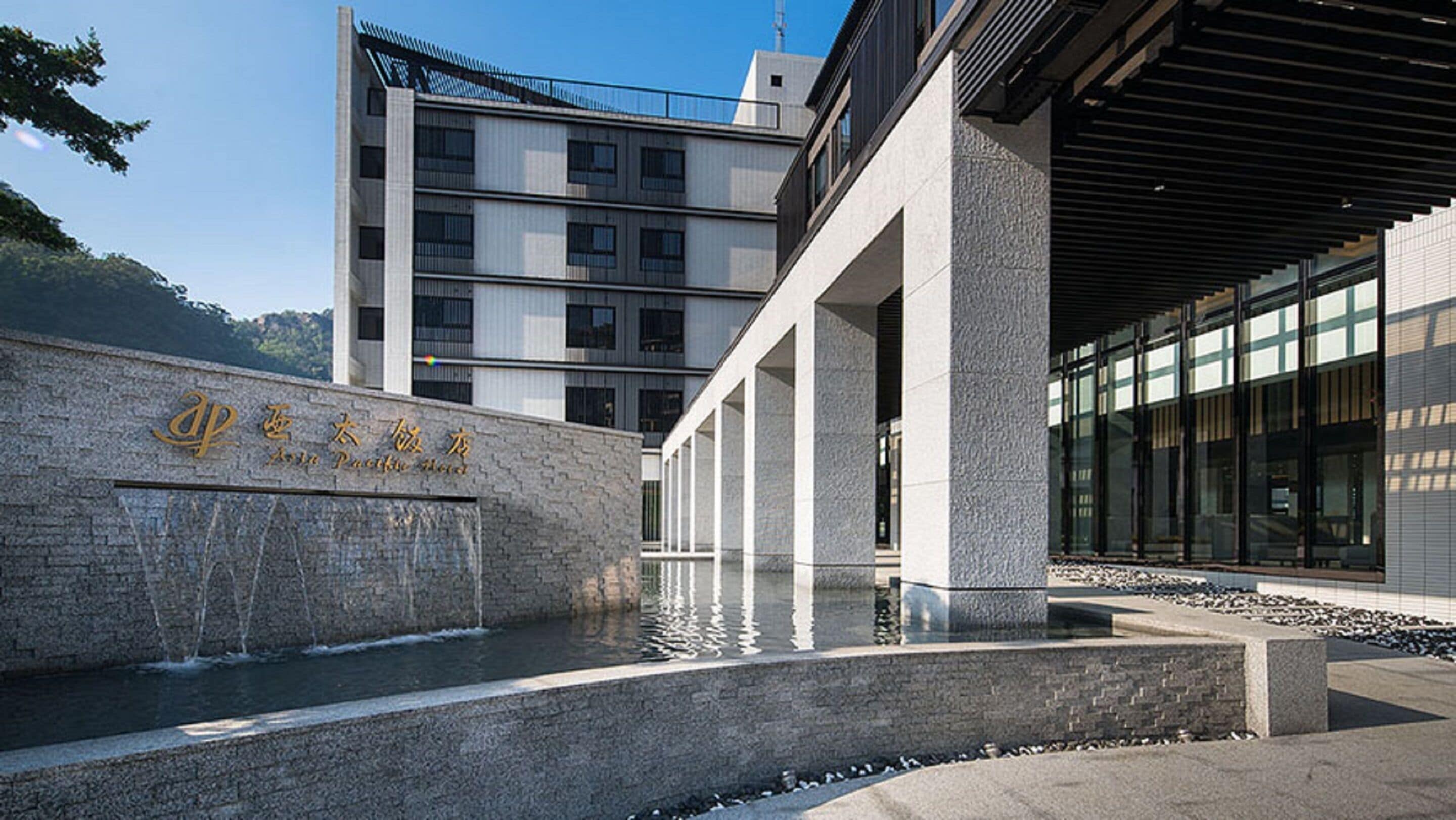 A modern building with a stone facade and a water feature in front.