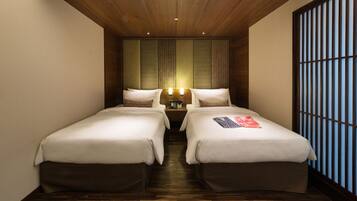 A hotel room with two single beds, a wooden ceiling, and a traditional Japanese shoji screen on the right.