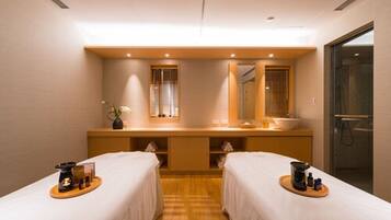 A hotel room with two beds, a wooden vanity with a mirror, a sink, and a shower area.