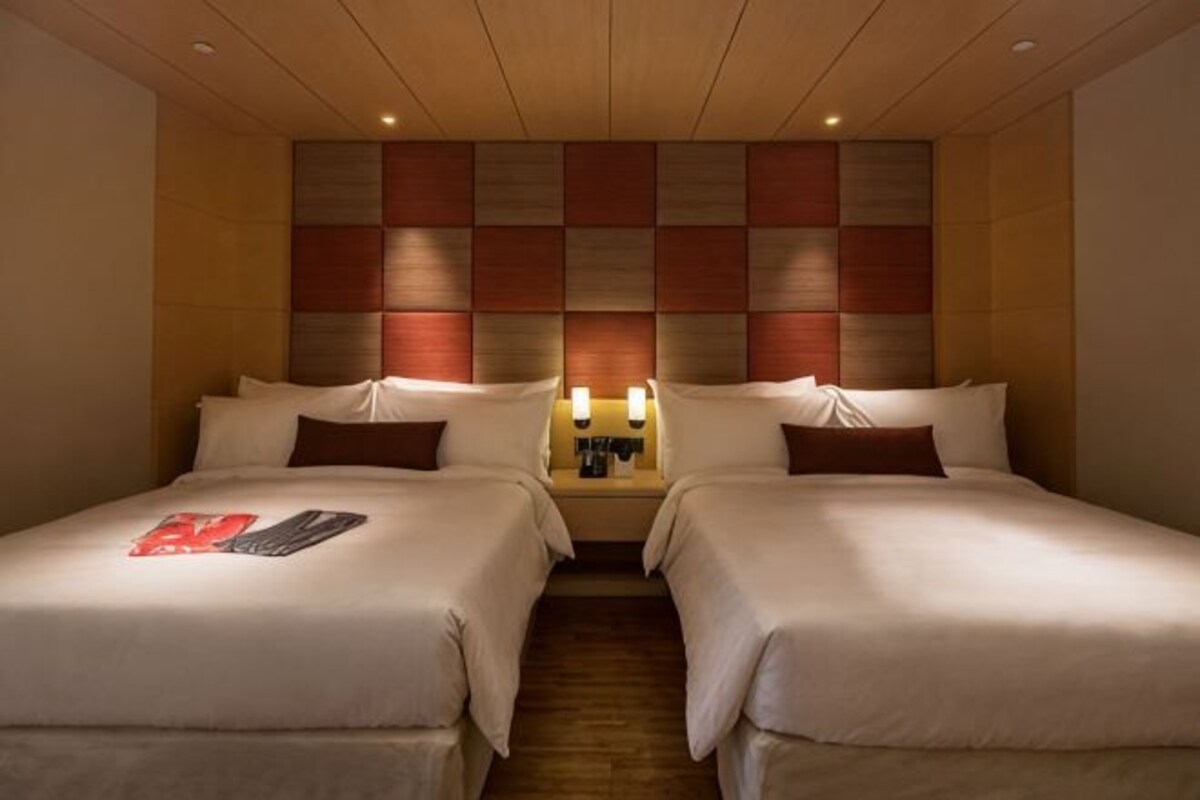 A hotel room with two beds, a wooden ceiling, and a wall with a geometric pattern.
