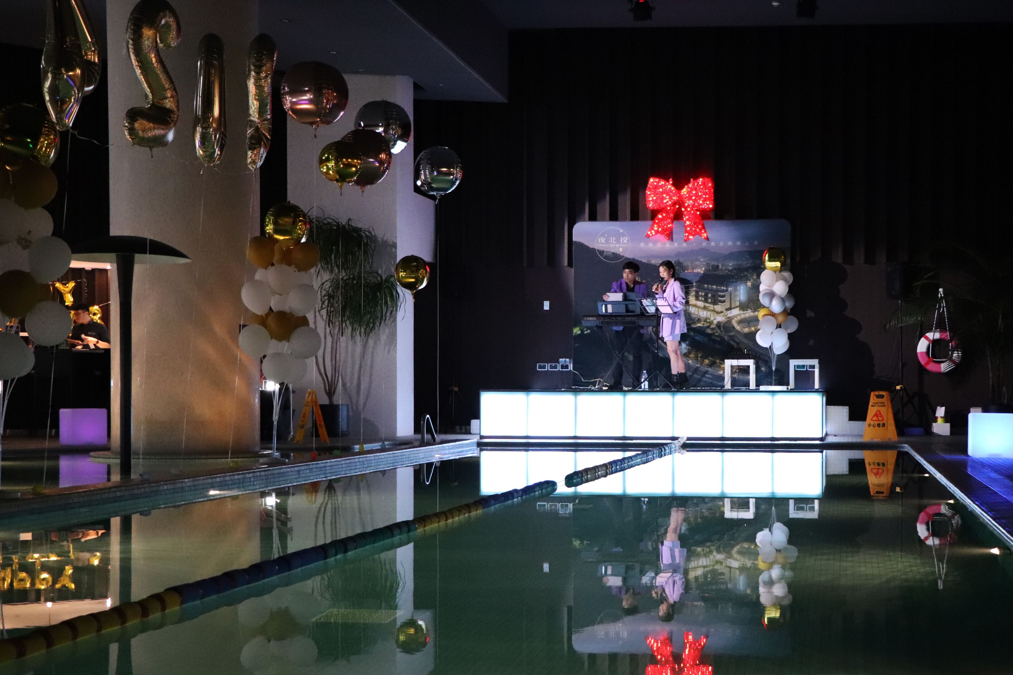 Un escenario con globos y un gran lazo rojo decorativo.