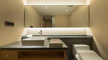 Un baño moderno con un espejo grande, un lavabo, un inodoro y un armario.