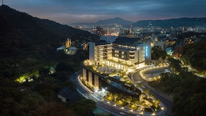 A modern hotel with a curved driveway, surrounded by greenery and a mountainous backdrop. - Asia Pacific Hotel Beitou (Taipei)