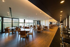 A spacious dining area with wooden tables and chairs, large windows, and a long counter with seating. - Asia Pacific Hotel Beitou (Taipei)