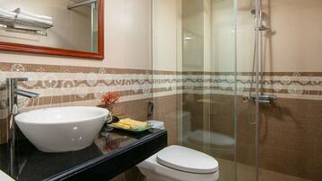 A modern bathroom with a large white sink, a toilet, and a glass-enclosed shower.